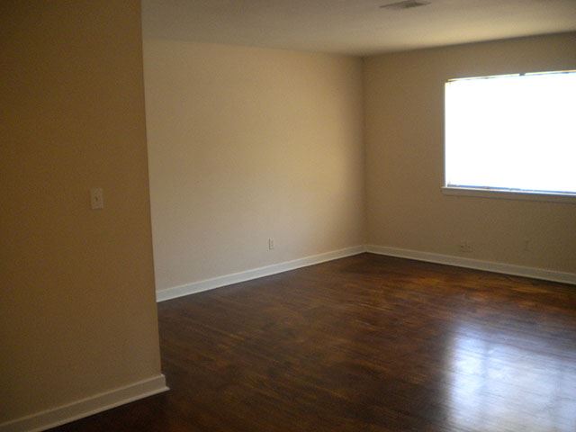 an empty room with wooden floors and a window
